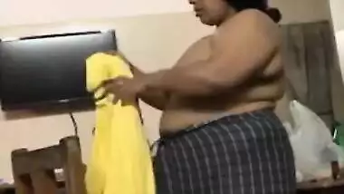 Fat Indian woman with big belly walks around the house with naked boobs