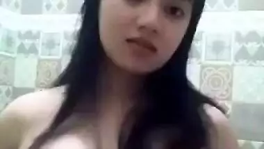 Sex model stands in front of mirror and squeezes own big natural tits